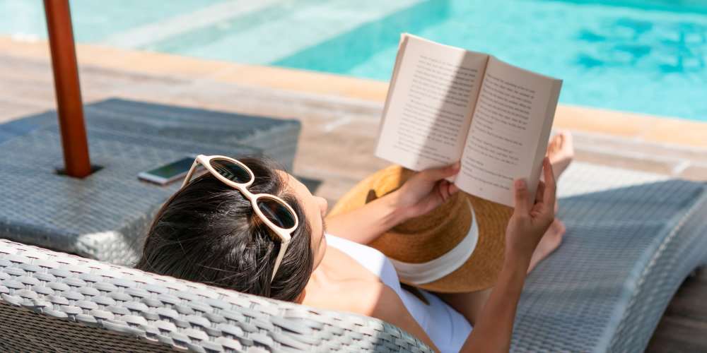Resident reading by the pool at Tides on Hulen in Fort Worth, Texas