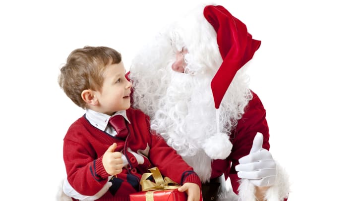 Santa Claus with a young boy holding a present. 