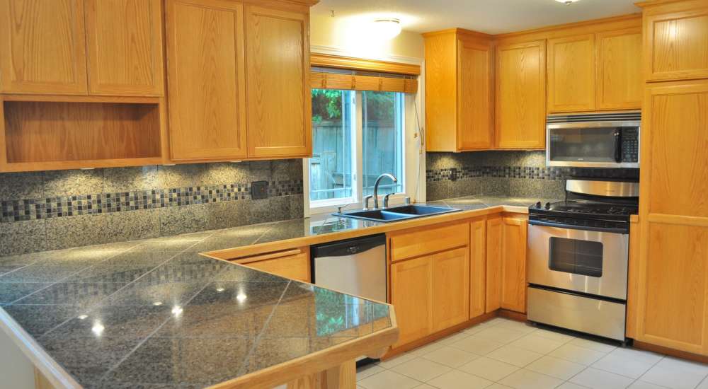 Modern kitchen with wooden cabinets and tile flooring at South Sound Residential in Lakewood, Washington