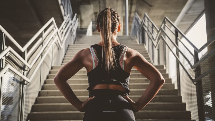 A woman facing a set of concrete stairs getting ready to start her workout.
