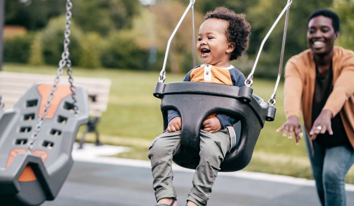 Child swing as mom pushes him at the playground at Mary Harvin House in Baltimore, Maryland