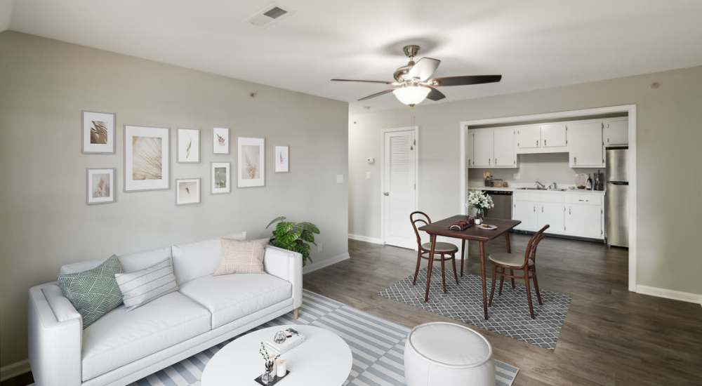 Spacious living room with ceiling fan and wood-style flooring overlooking into kitchen at The Element At Wilma Rudolph in Clarksville, Tennessee