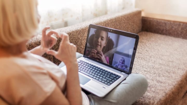 A senior-aged woman talks to a young girl on video chat.