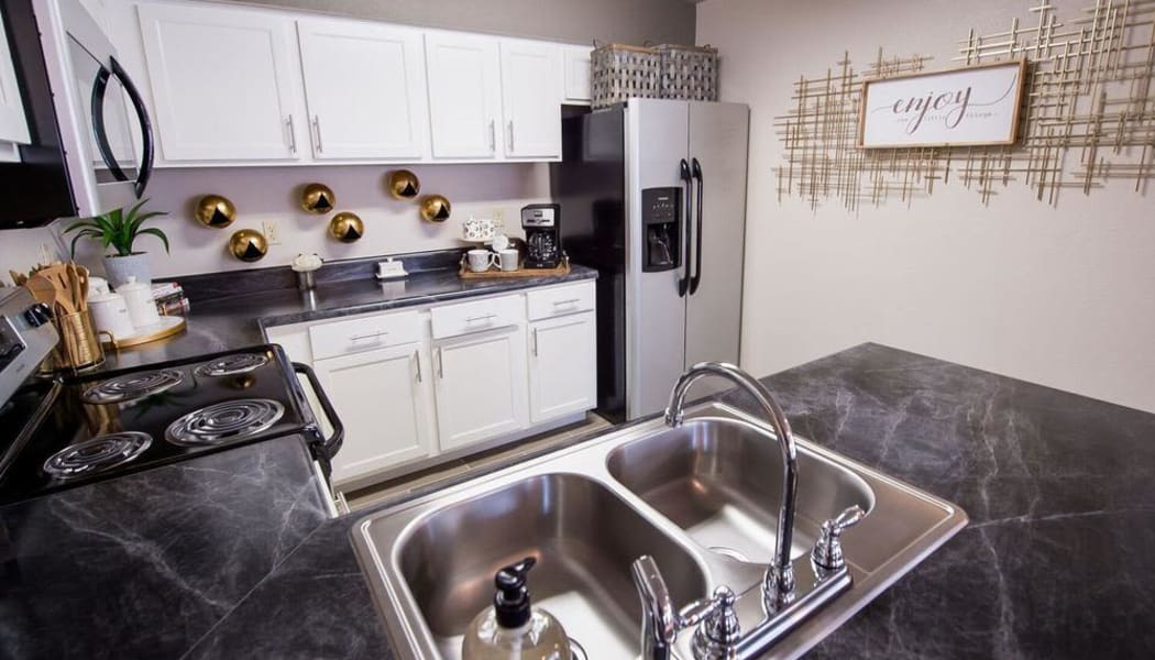 Modern kitchen with granite counters at Watercress Apartments in Maize, Kansas