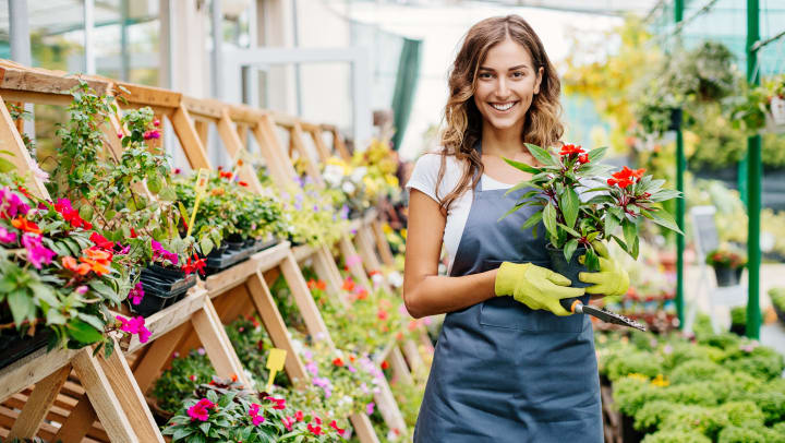 A woman holding a potted plant at a Spring nursery.