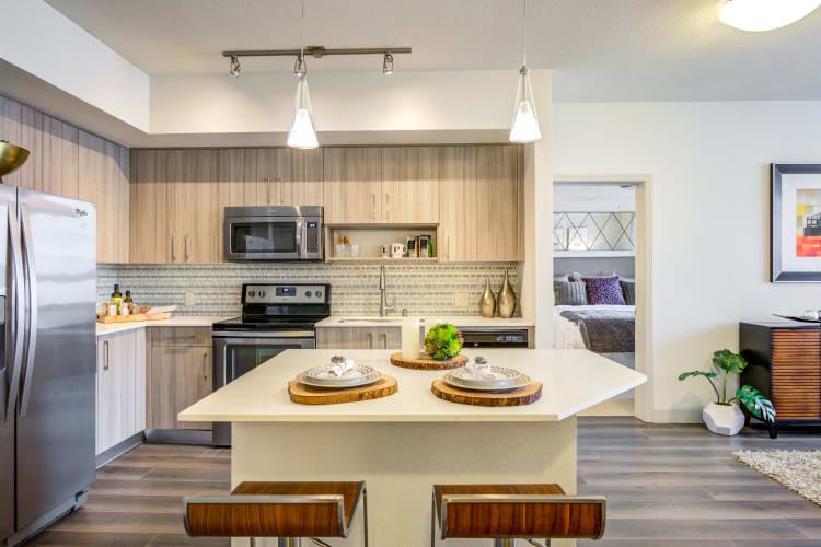 Beautiful gourmet kitchen with antique-style cabinetry and granite countertops in a model home at Loftin Place Apartments in West Palm Beach, Florida