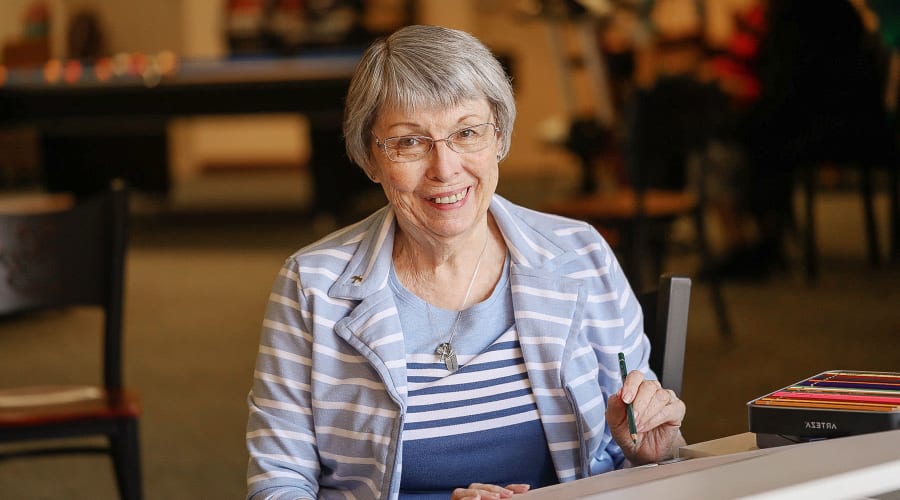 Resident smiling for the camera while taking an art class at Cascade Park Vista Assisted Living in Tacoma, Washington