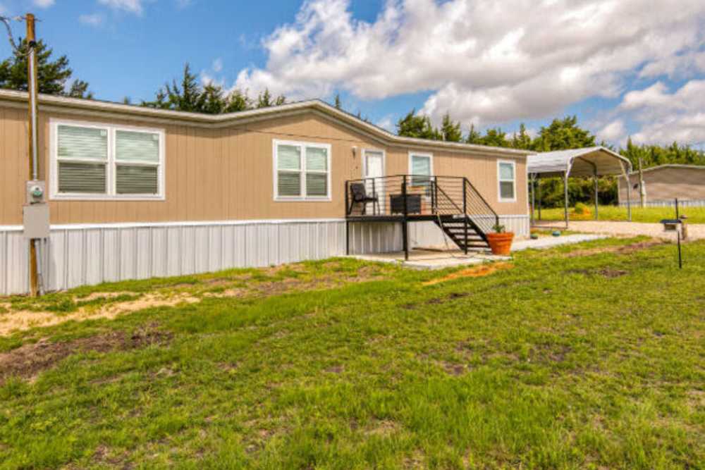 Exterior view of the apartment building with lawn in front at IC Creek Ranch in Leonard, Texas