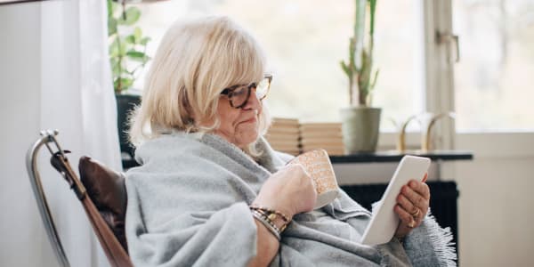 Resident wrapped in a blanked drinking coffee and looking at her smart phone at Retirement Ranch in Clovis, New Mexico