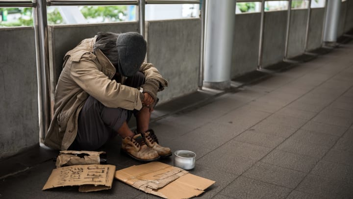 Homeless person seeking help from those nearby