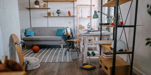 Spacious living room with couch, study table, wood-style flooring and wooden slabs for showcase purposes at Reidy Creek Apartments in Escondido, California