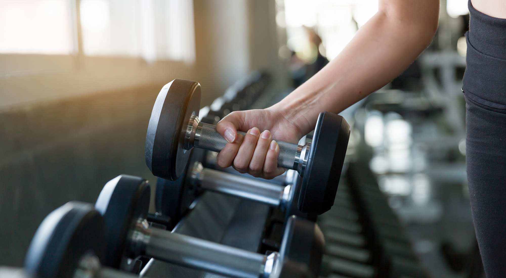 A person lifts a dumbbell in a gym at Granite Creek in Rocklin, California.