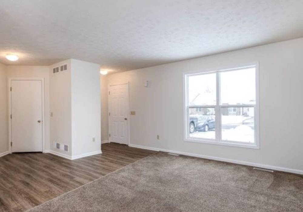 Living room with carpet flooring and large window at Unionville Station Townhomes in Hilton, New York