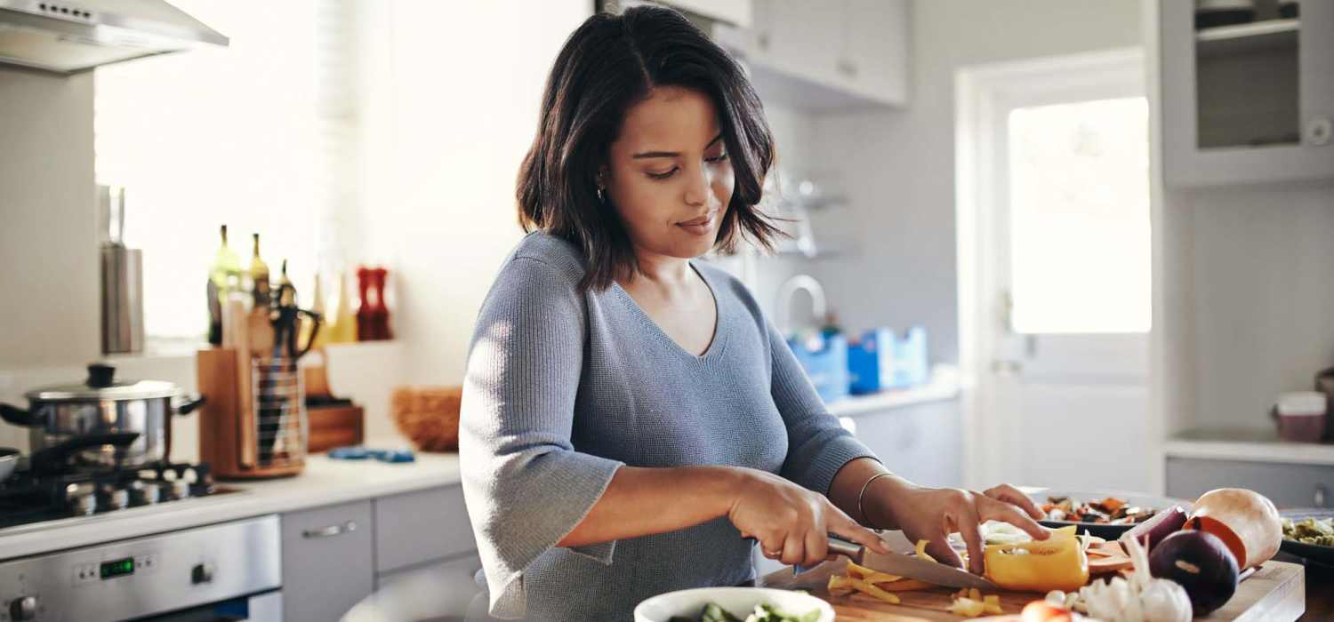 Resident woman preparing food in the kitchen at Excelsior Apartments in Brevard, North Carolina