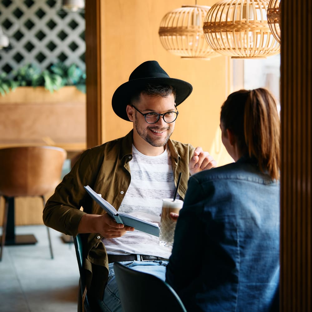 Residents chatting and reading in a modern cafe near Hilton Village II Apartments in Hilton, New York