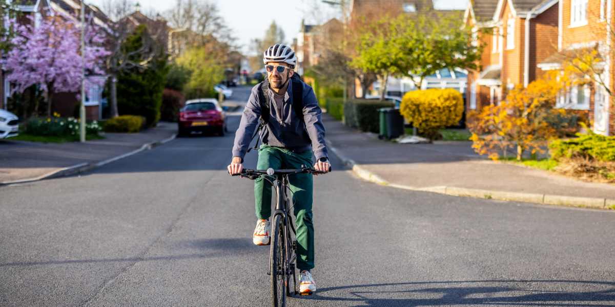 Man riding a bicycle on a residential street at Avia Lofts at Maple Road in Amherst, New York