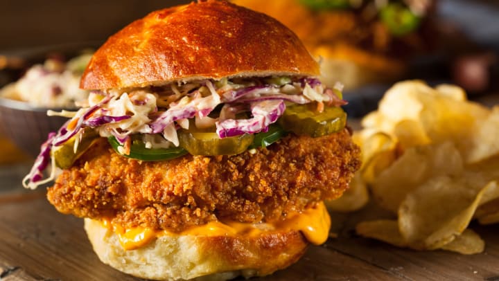 Fried chicken sandwich on a bun with red cabbage, pickles, and jalapenos
