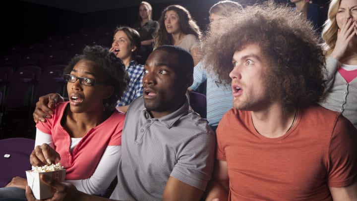 A group of people in a movie theater. They all look shocked.  