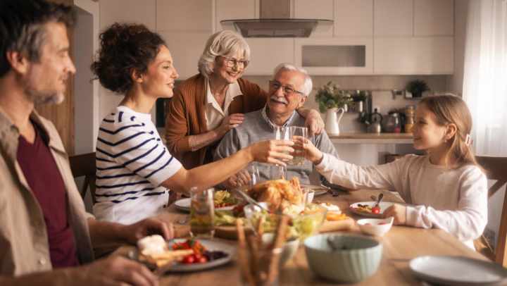 Group of people gathered around a dining table sharing a meal with dishes, drinks, and food spread across a well‑lit kitchen setting at {{location_name}} in {{location_city}}, {{location_state_name}}.