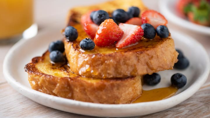 Plate of French toast with berries and syrup. 