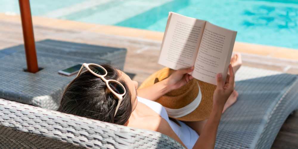 Resident enjoying a book by the poolside at Desert Meadows in Lancaster, California