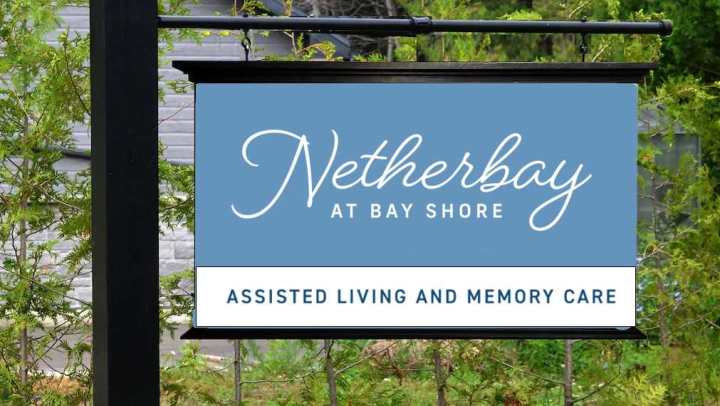 Blue sign with white Netherbay logo that also says Assisted Living and Memory Care