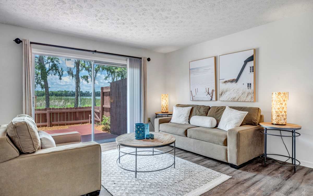 Spacious living room with large couch, coffee table and wood-style flooring at Lake Carlton Arms in Lutz, Florida
