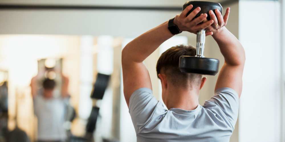 Resident using dumbbell in fitness center at Desert Meadows in Lancaster, California