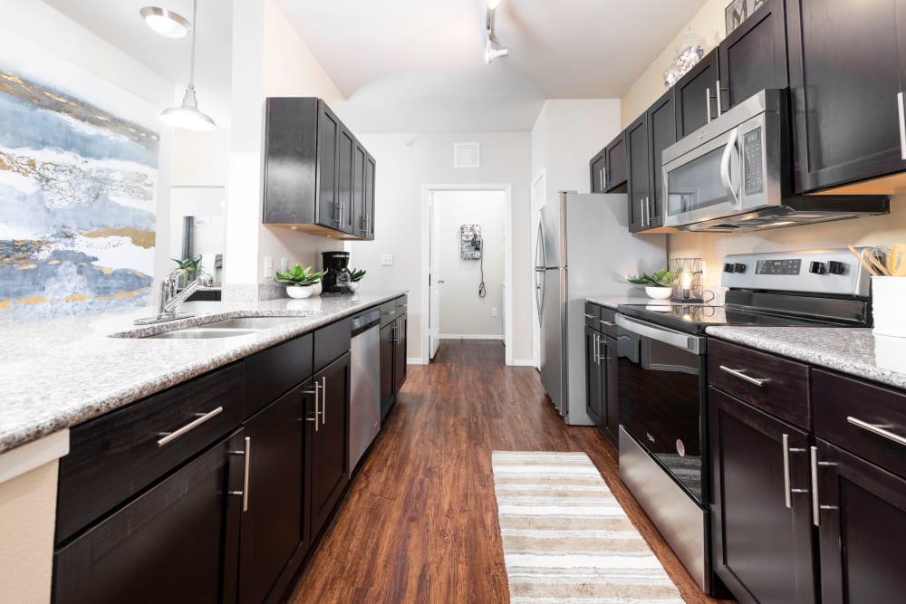 Hardwood flooring and rich, dark wood cabinetry in a model home at Carrington Oaks in Buda, Texas