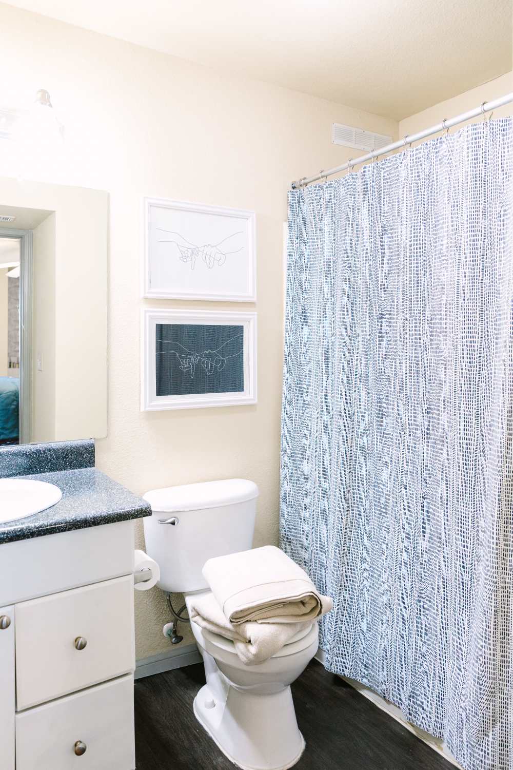 Bathroom with vanity sink, toilet, and patterned shower curtain in bright space at The Holly in Lubbock, Texas
