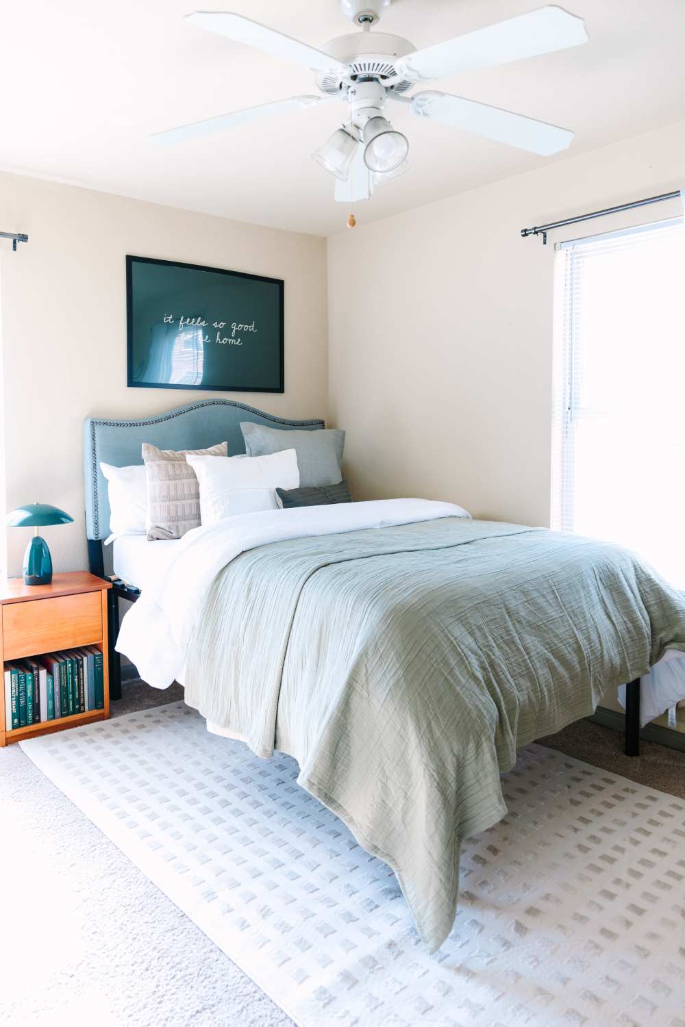 Bright bedroom with bed, nightstand, ceiling fan, and windows with natural light at The Holly in Lubbock, Texas