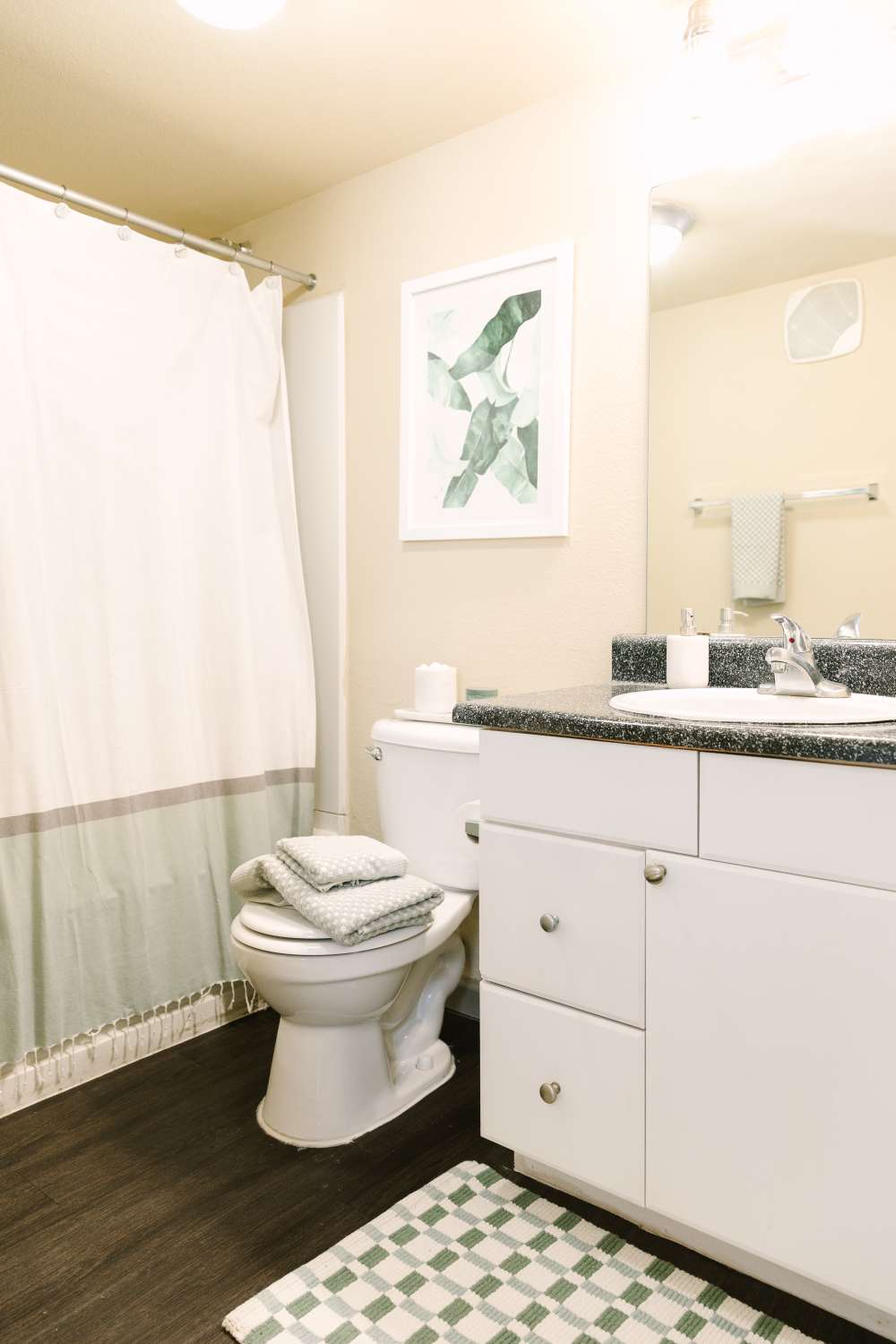 Bathroom with vanity sink, toilet, and shower curtain in bright neutral space at The Holly in Lubbock, Texas