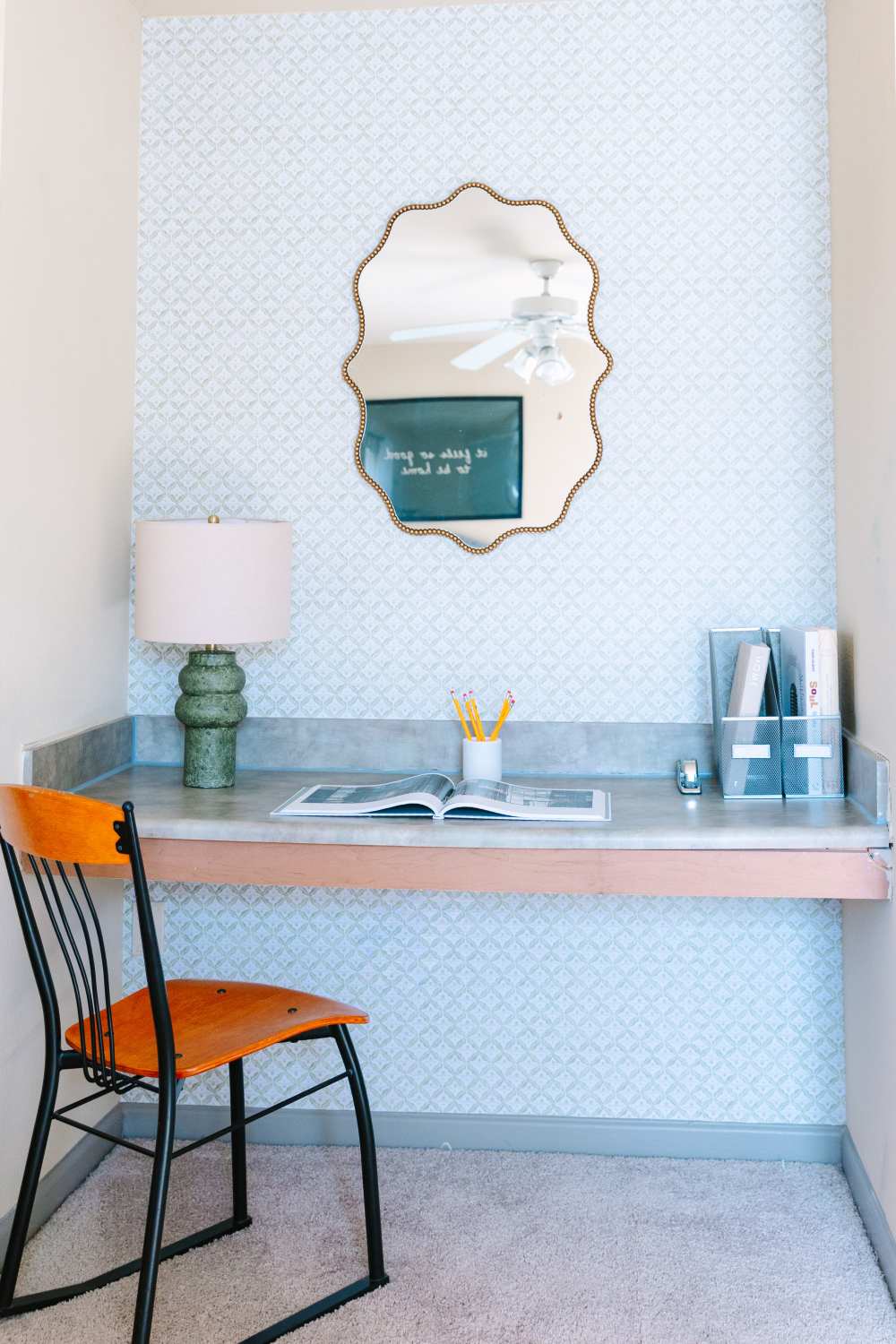 Minimalist desk setup with chair, lamp, mirror, and office supplies on counter at The Holly in Lubbock, Texas