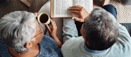 Resident couple reading a book while drinking coffee at MBK Senior Living in Irvine, California