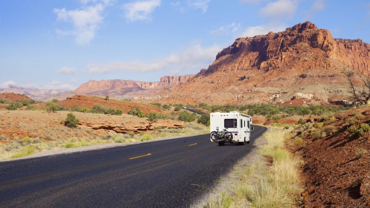 RV driving down the open road in a rocky landscape