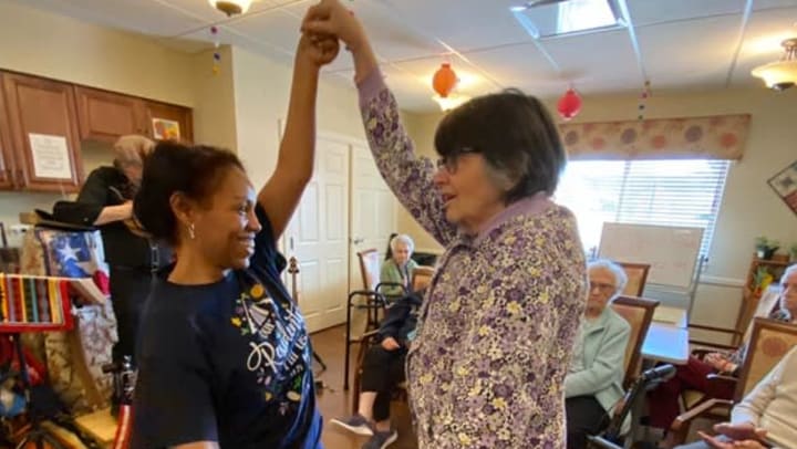 A woman and a senior as dancing partners at Senior Living Community in {{location_city}}, {{location_state_name}}