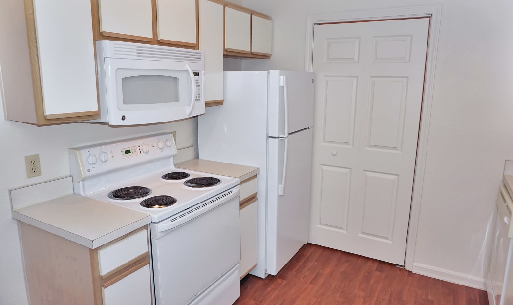 Modern kitchen with white appliances and hardwood floors in model home at Renaissance St. Andrews in Louisville, Kentucky