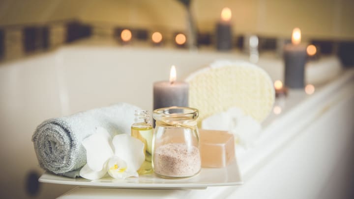 a bathroom with a tray of salts, a towel, and a candle
