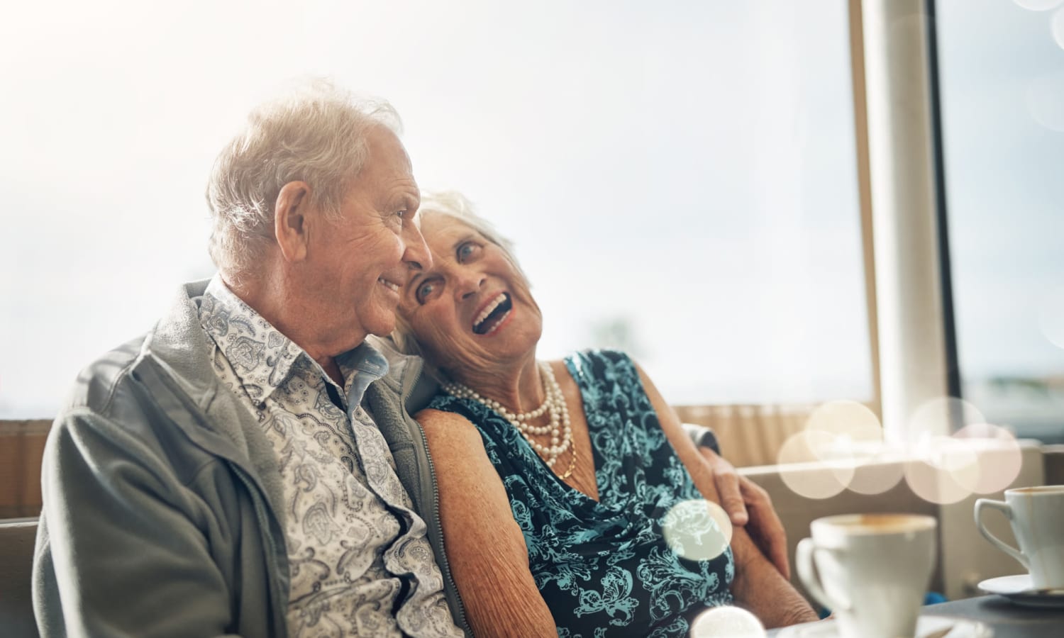 Senior couple laughing and enjoying coffee at Sandpiper Courtyard in Mt. Pleasant, South Carolina