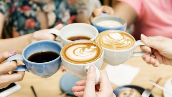 group of friends holding up cups of coffee from shops in Midland