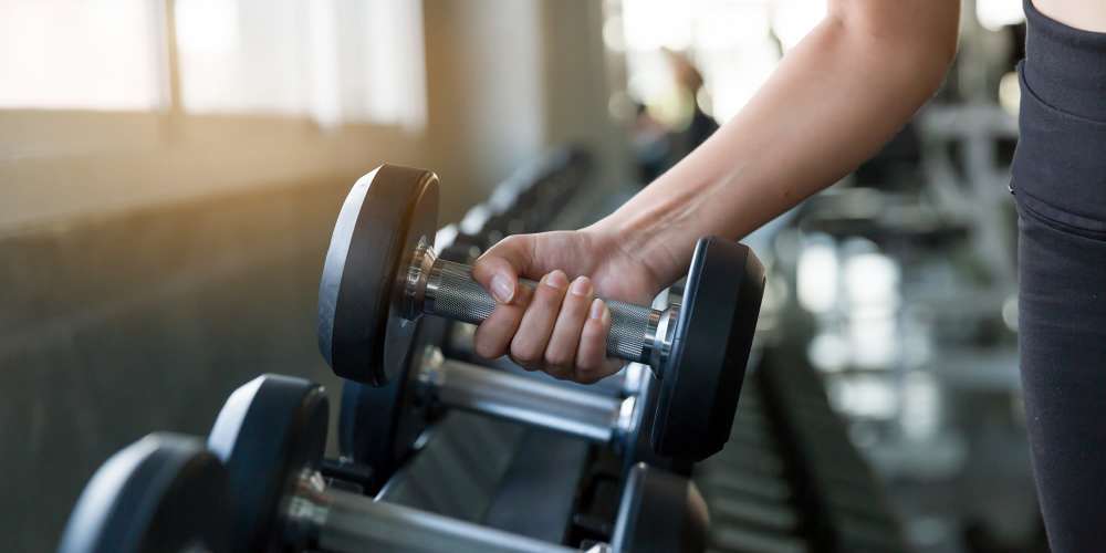 Residents lifting weights in a fitness center at BB Living Seven Shores in Naples, Florida