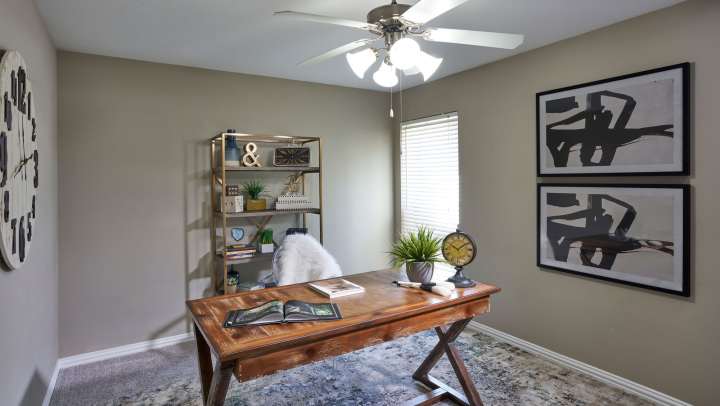 A comfortable workspace with a desk, chair, and framed pictures.
