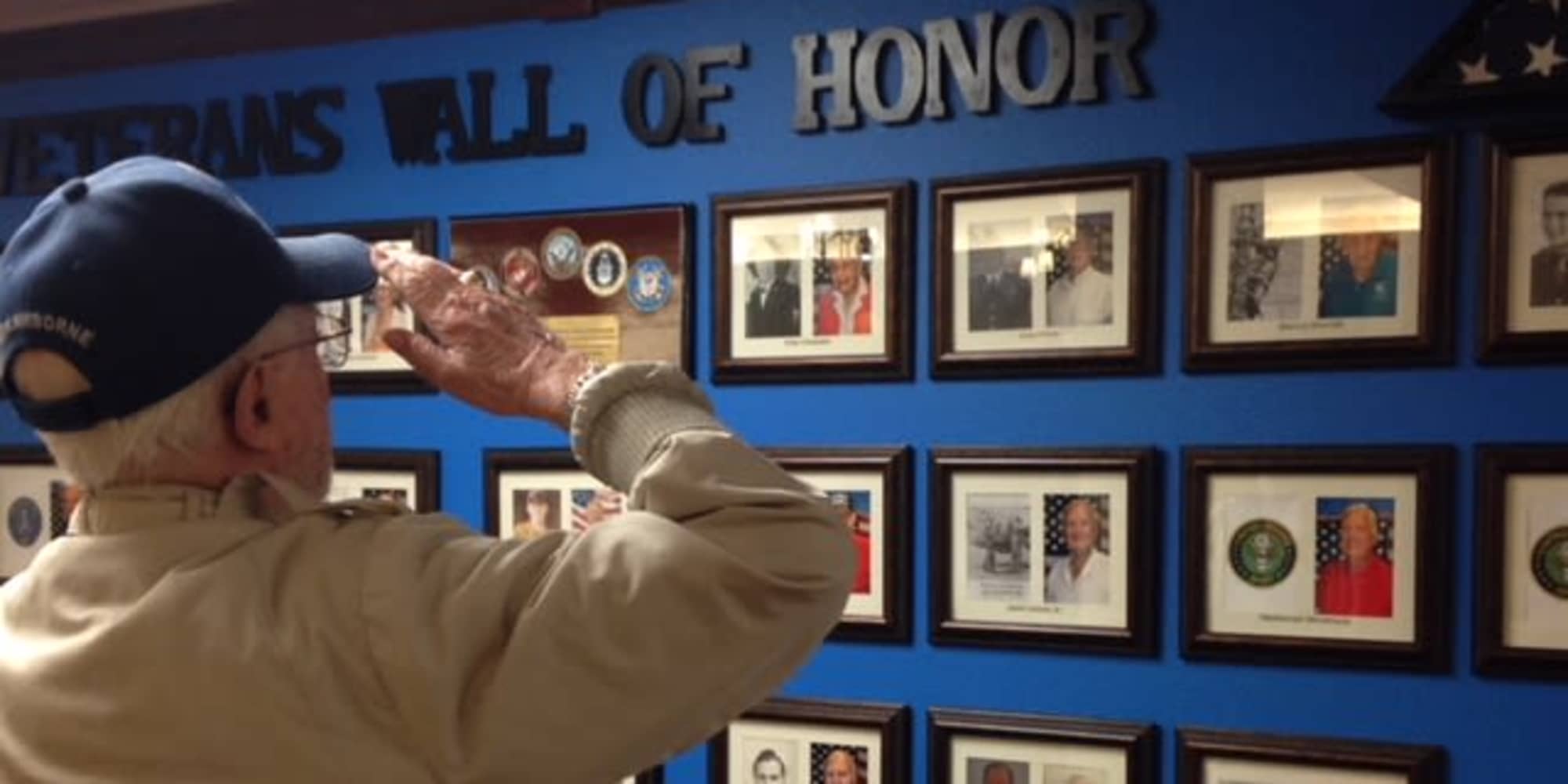 A veteran resident saluting the veterans wall of honor at Magnolia Heights Gracious Retirement Living in Franklin, Massachusetts