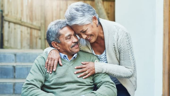 Woman hugs an elderly man seated in a wheelchair at Brightwater Senior Living