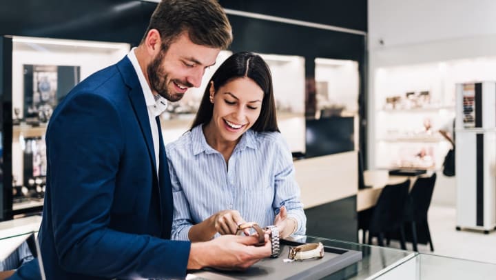 Man and woman smiling and looking at watches over a display case