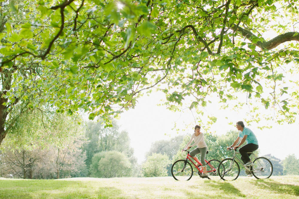 Resident couple riding bikes outside near an Amira community