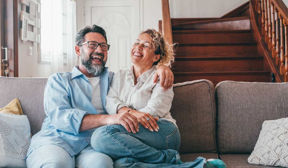 A couple of residents embracing themselves in their living room at Athens Vista Senior Apartments in Los Angeles, California