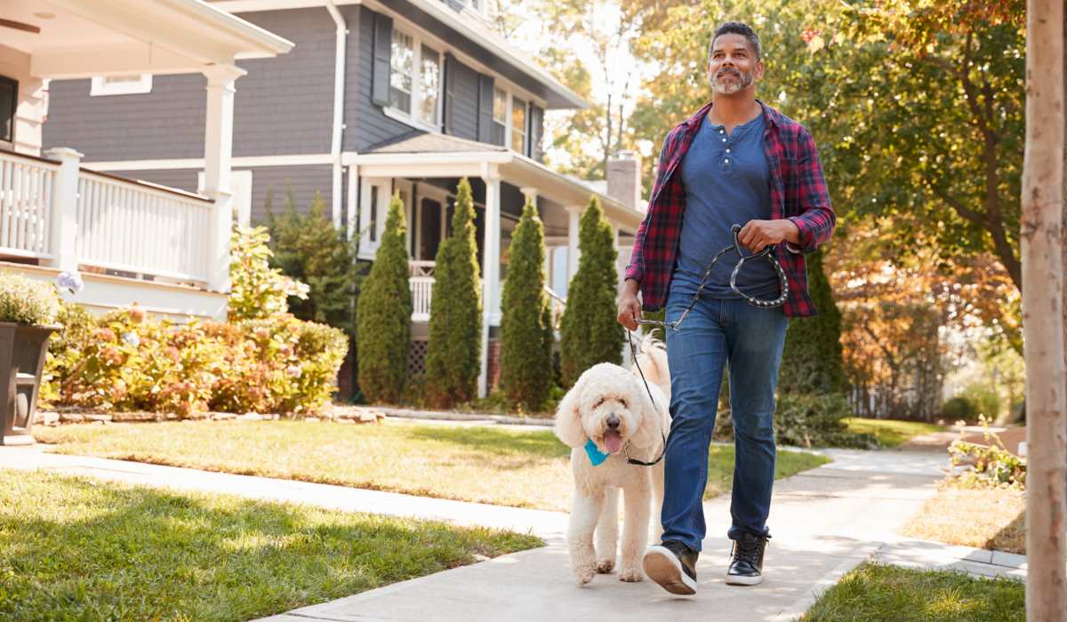 Man walking dog on sidewalk near Clarkwood Greens in Warrensville Heights, Ohio