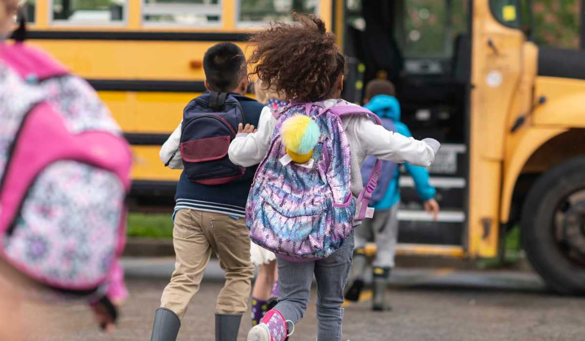 Children running towards a school bus near Collins Crossing Apartments in Carrboro, North Carolina 