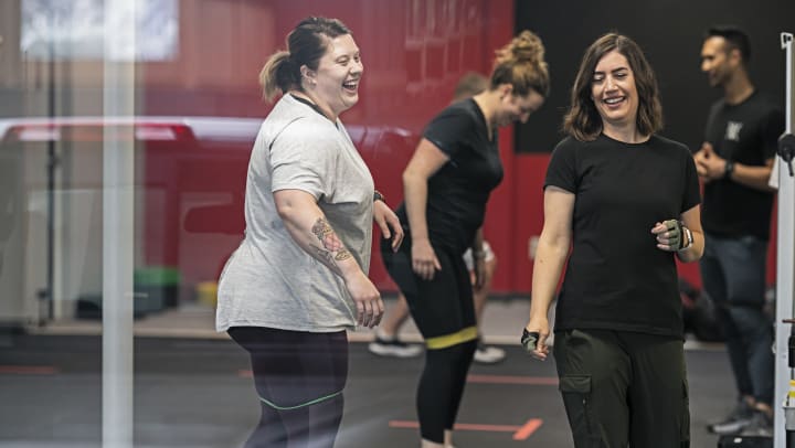 A group of laughing women enjoy a workout class at a gym in Buda